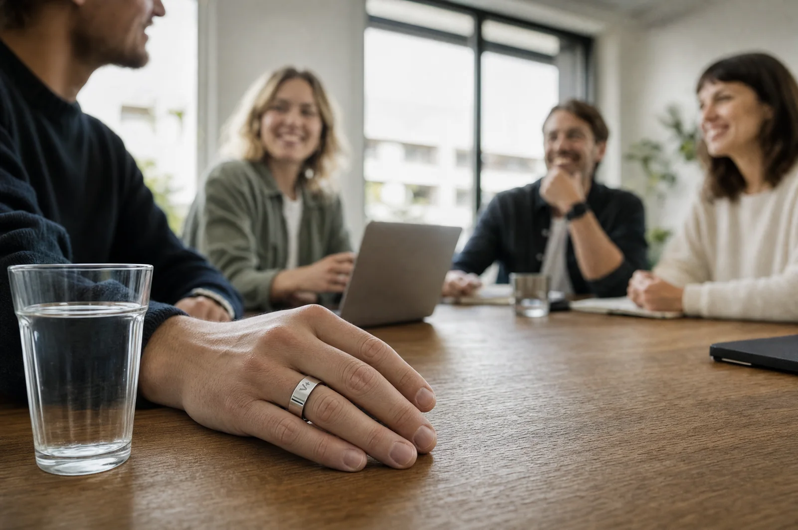 A team discussing employee wellbeing around a table while a colleague wears a smart ring